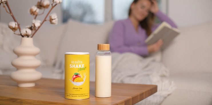 Tisch mit BEAVITA Shake und Frau im Hintergrund